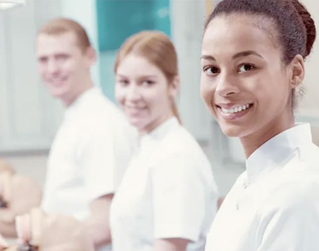 Drei lächelnde Zahnmedizinstudent:innen