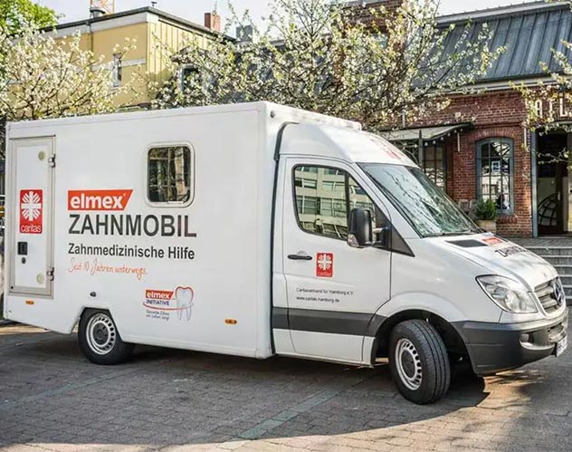 Drei lächelnde Zahnärzte stehen in einem Praxisraum